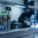 Person welding a metal rectangular block.